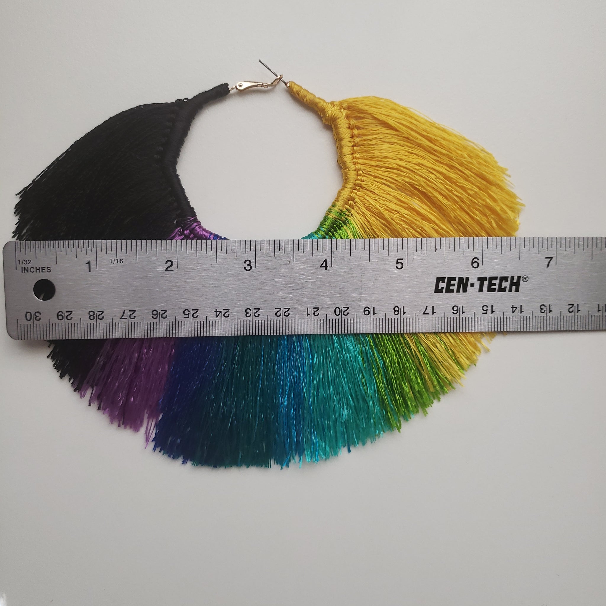 Fan shaped Multi-Colored Tassel Hoop earrings that are yellow, green, blue, purple, and black. Width measurement is 6.5 inches.